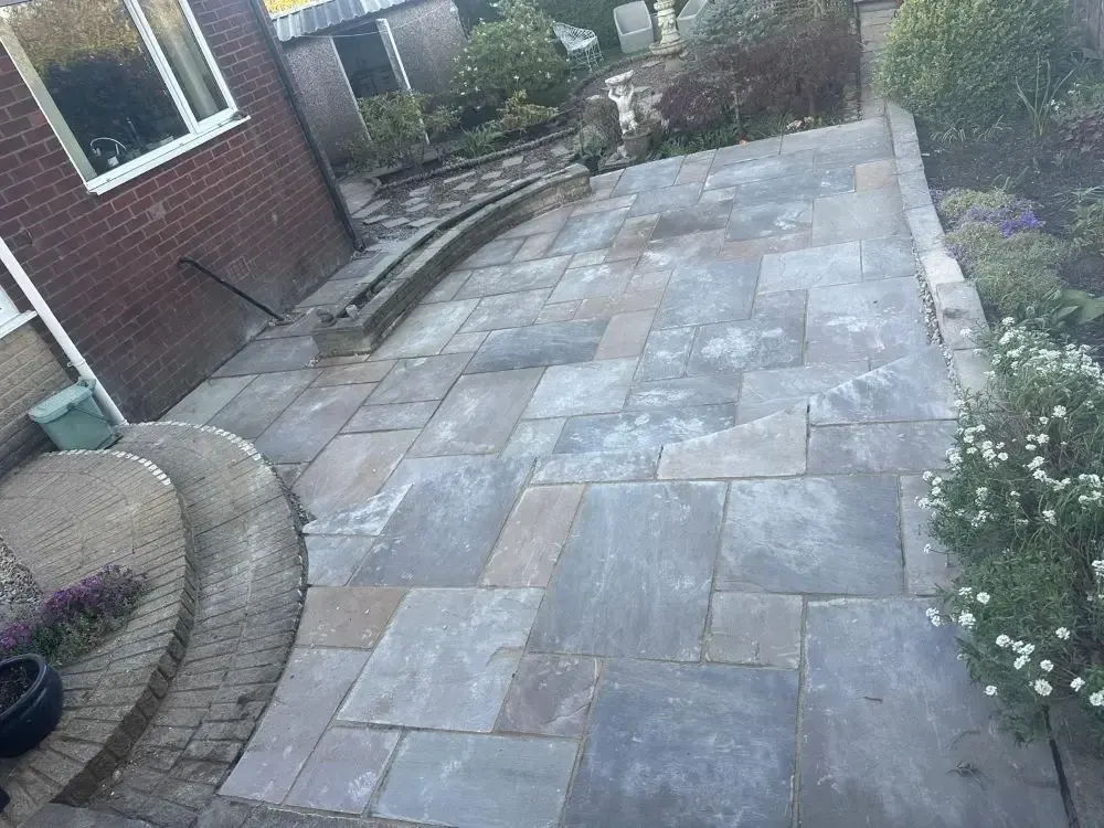 Sandstone patio with curved brick planter