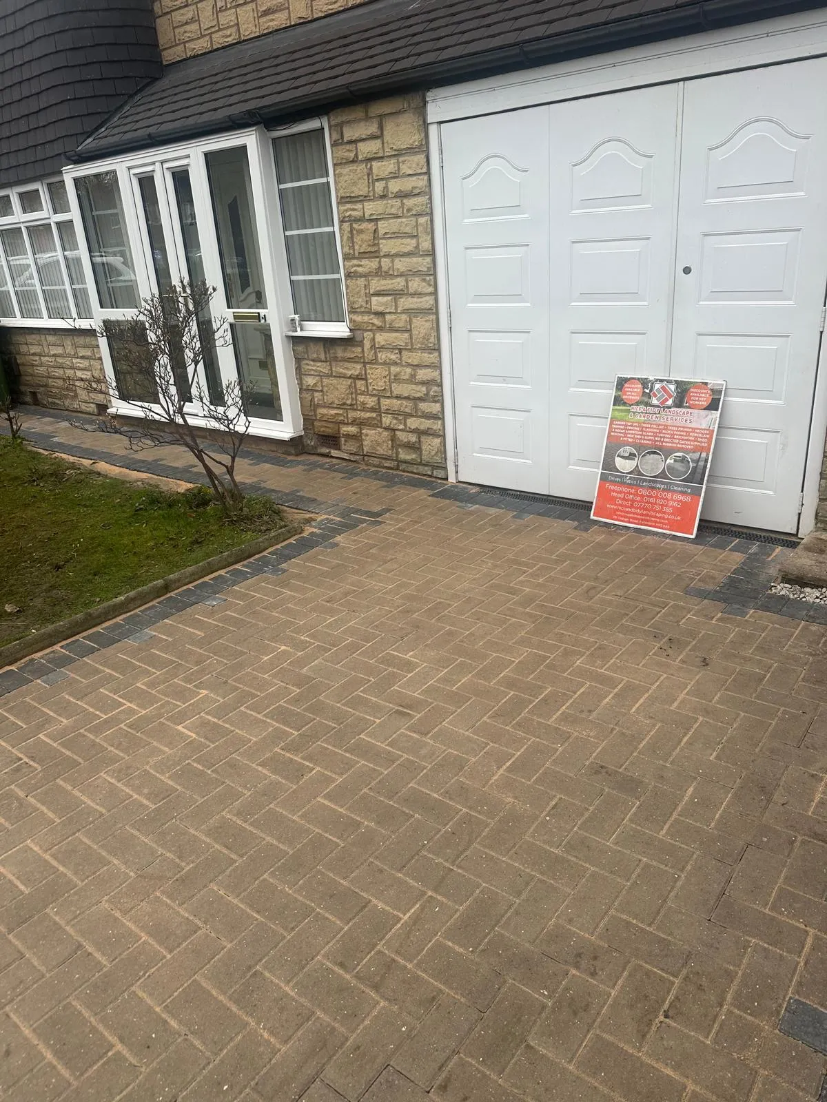 Block paved driveway to a white garage