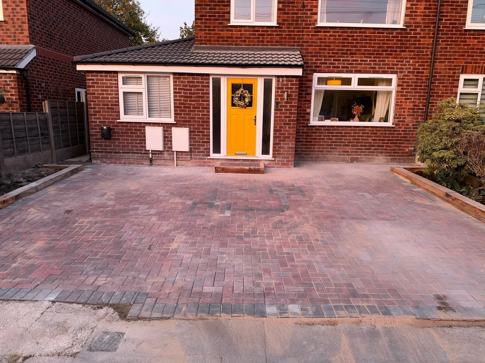 Block paved front driveway to a yellow door