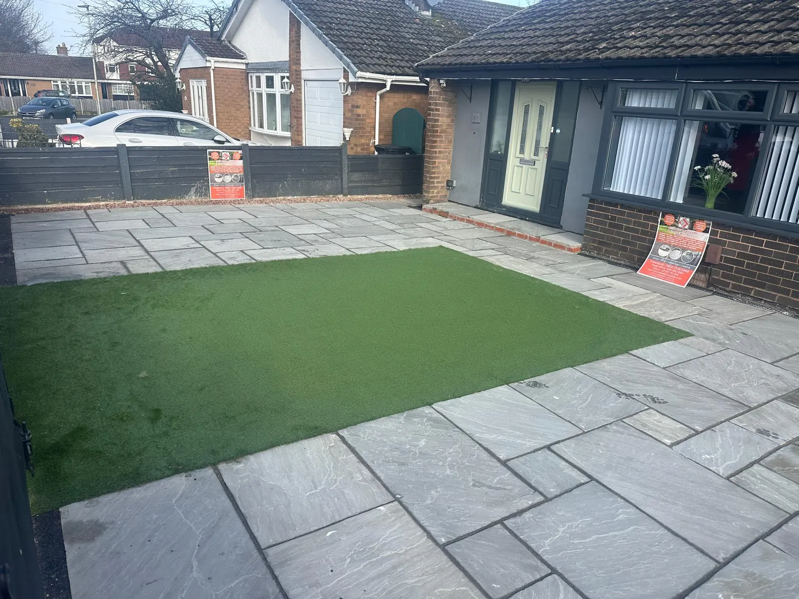 Front garden with an artificial lawn and sandstone paving