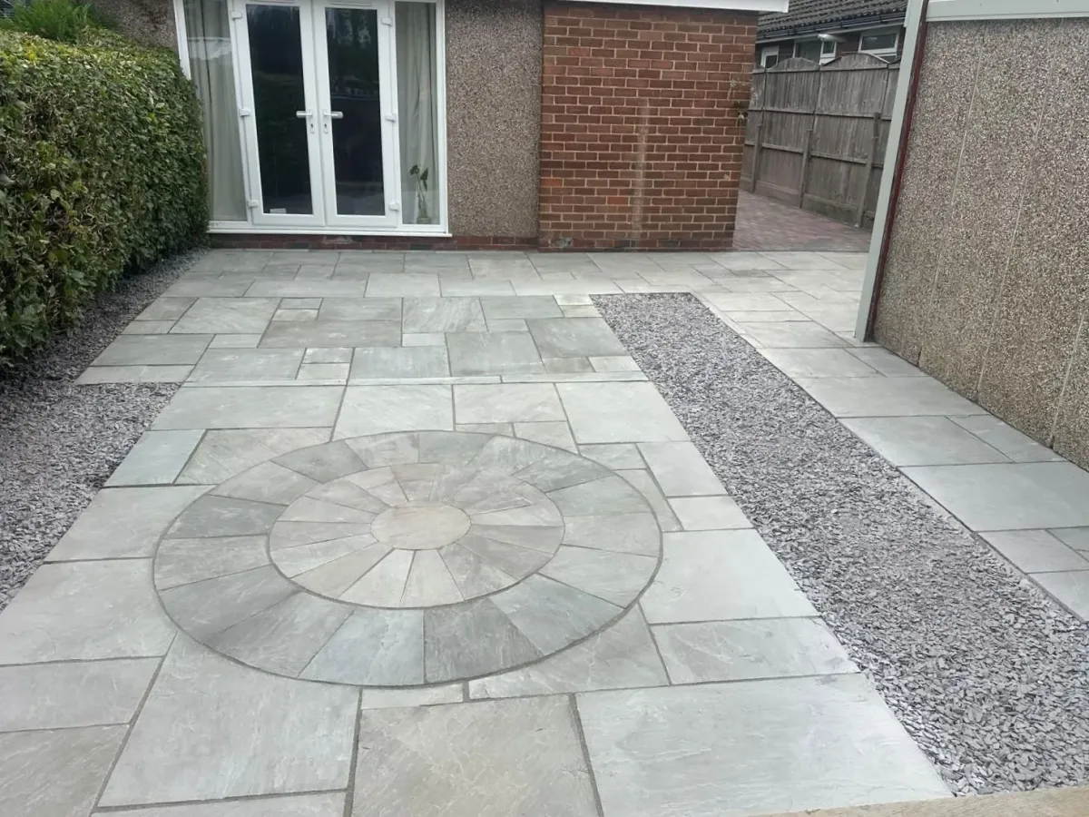 A grey sandstone patio with a circle feature and slate chipping borders, laid by Nice & Tidy in Manchester