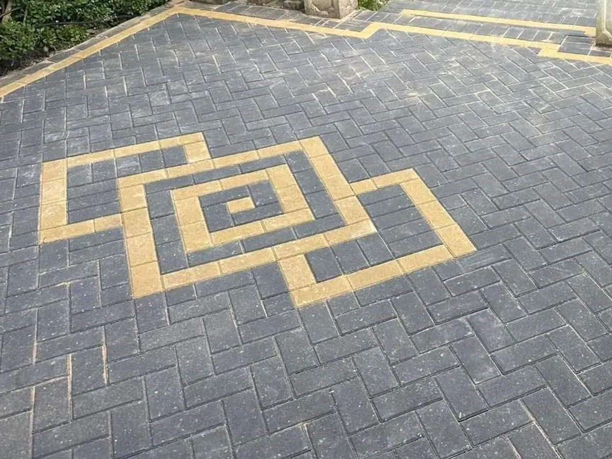 Charcoal herringbone block paved patio with a buff pattern inlay in Greater Manchester