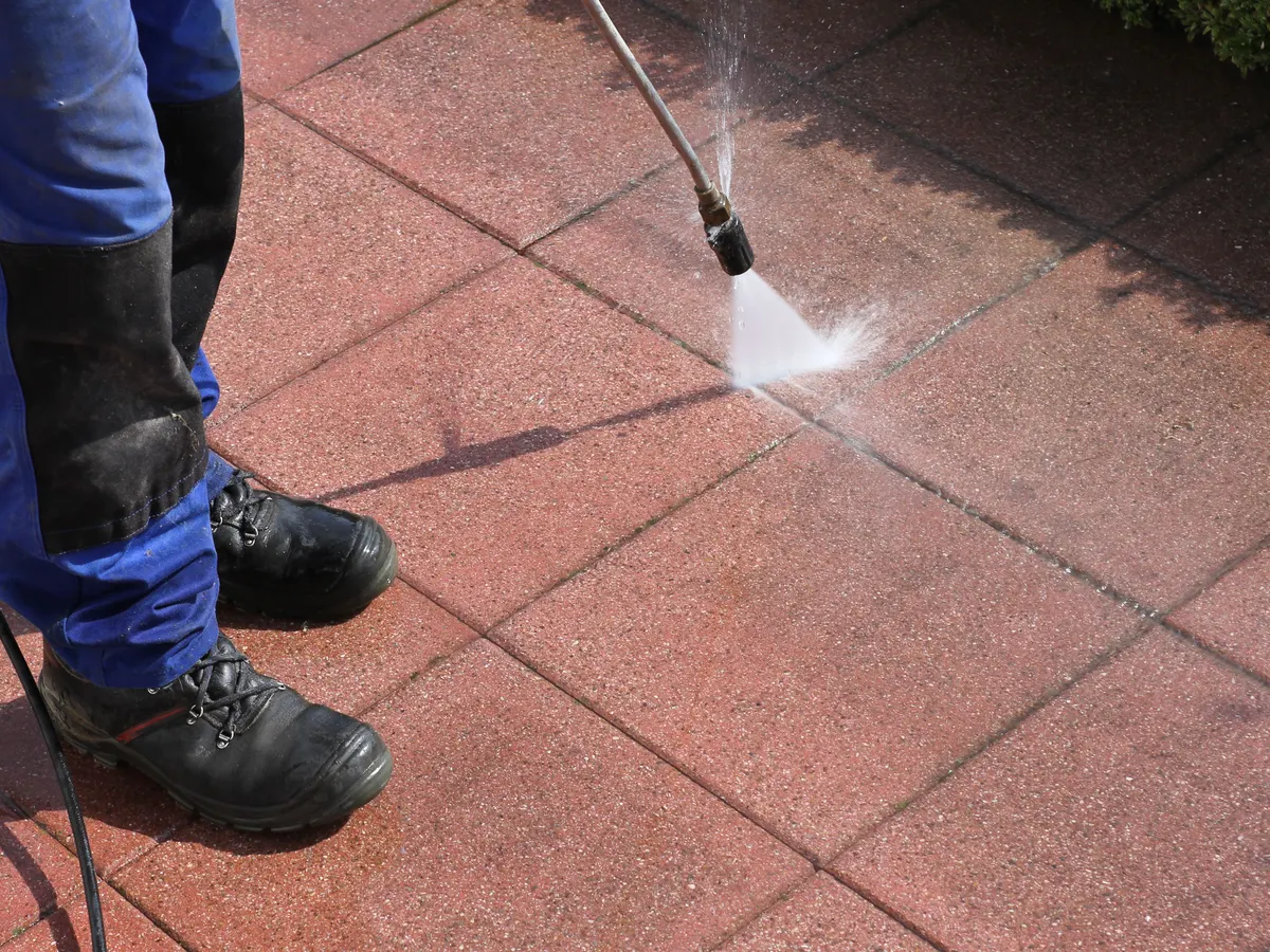 Red paving slabs being jet washed