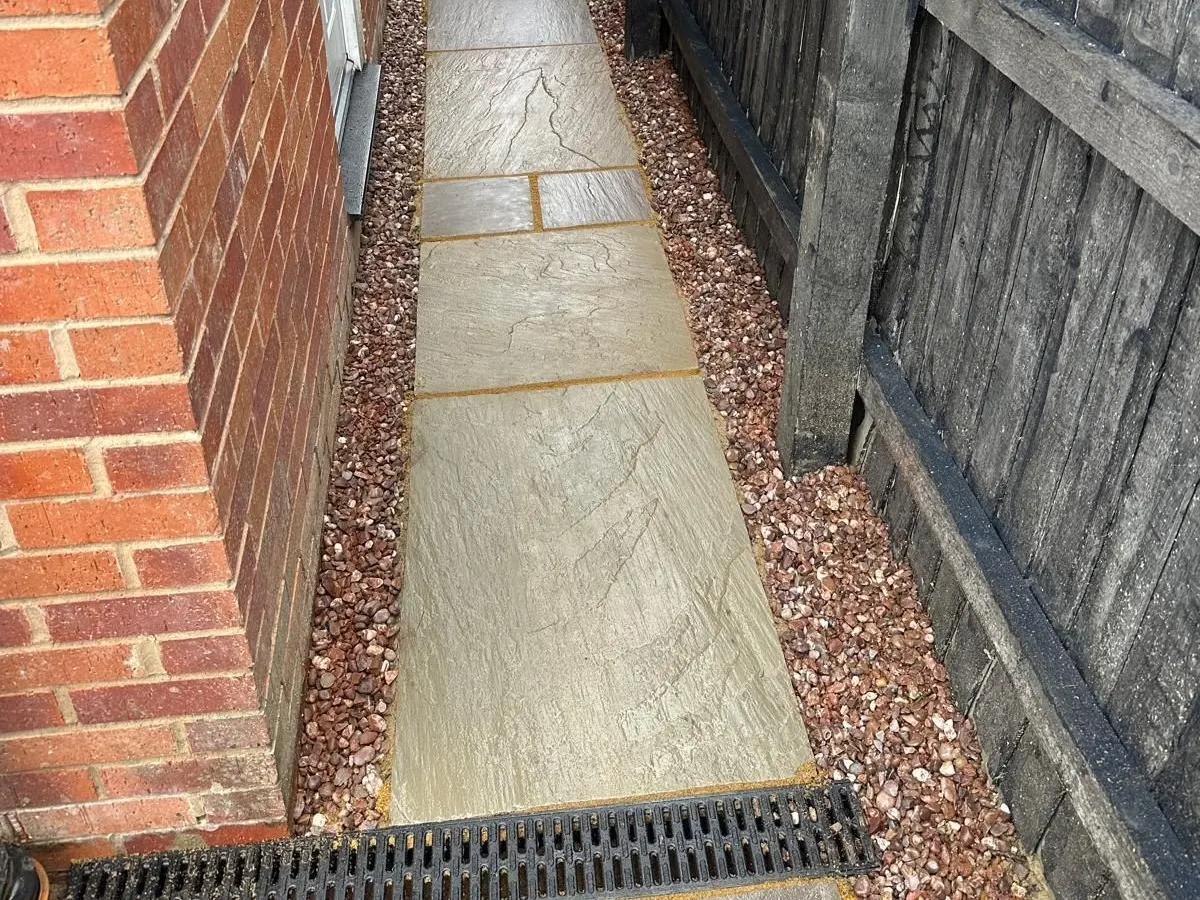 Sandstone side path with gravel margins and a drainage channel in Manchester