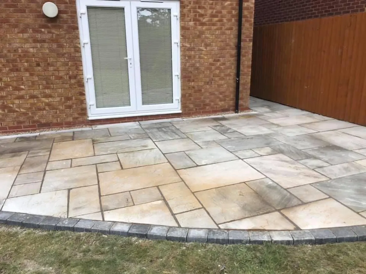 Light sandstone patio with a curved block edge in Manchester