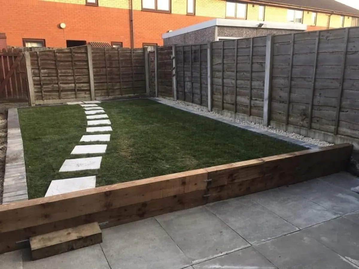 Sleeper retaining wall holding a raised lawn above a patio in Manchester